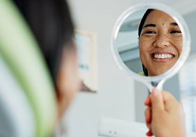 Woman smiling at reflection in dentist office