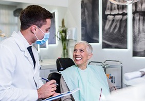 Dentist with clipboard talking to smiling patient