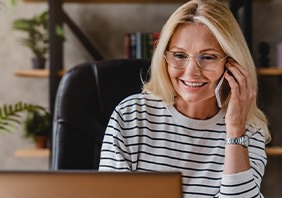 Woman with glasses smiling while talking on phone