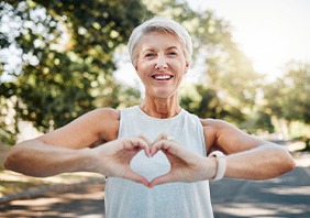 Smiling lady makes shape of heart with her hands