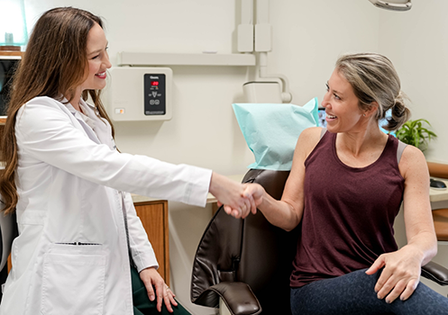 Dental patient shaking hands with her dentist