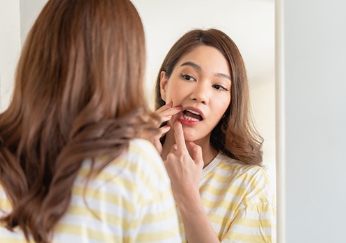 Patient looking in mirror while showing signs of gum disease 