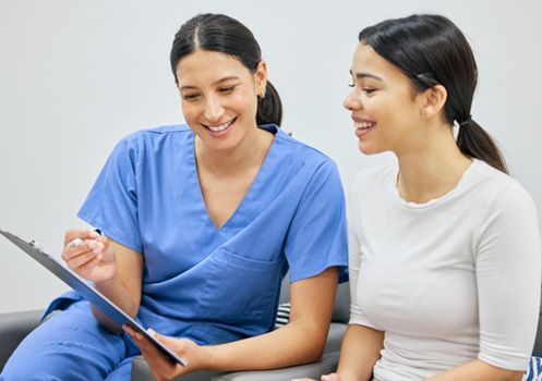 Dental staff member and female patient talking 