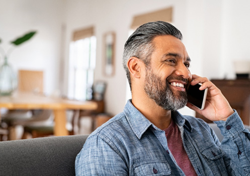 Man sitting on the couch calling his dentist’s office 