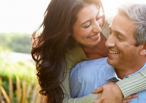 Middle-aged couple smiling after using their in-house membership plan in