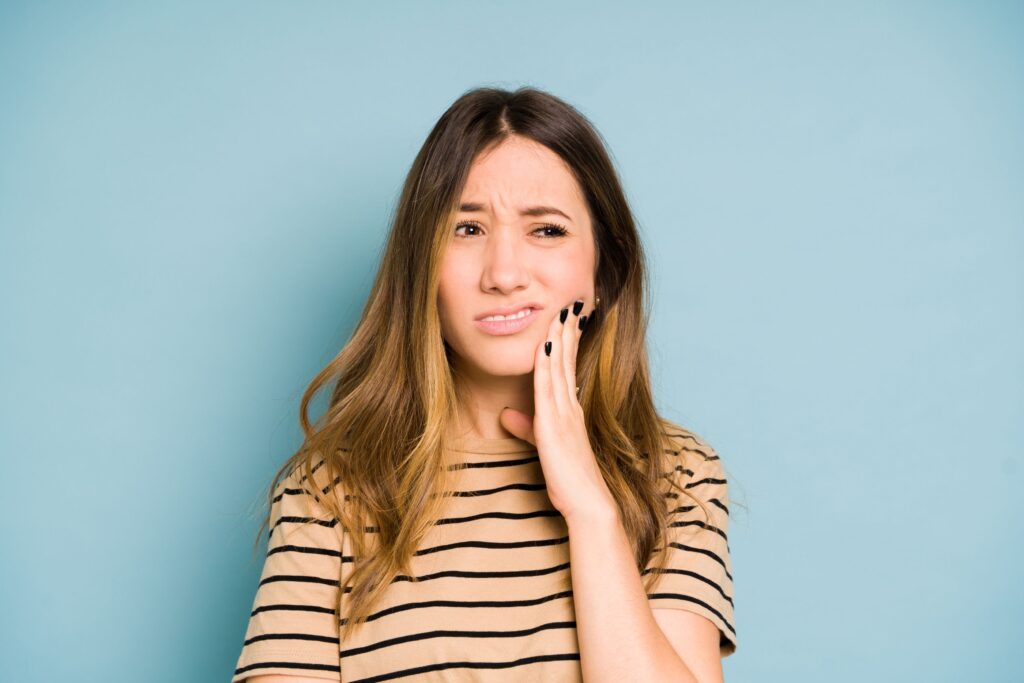 Woman holding her hand to her cheek in pain