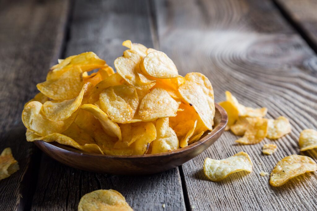 Plate of potato chips on wooden surface