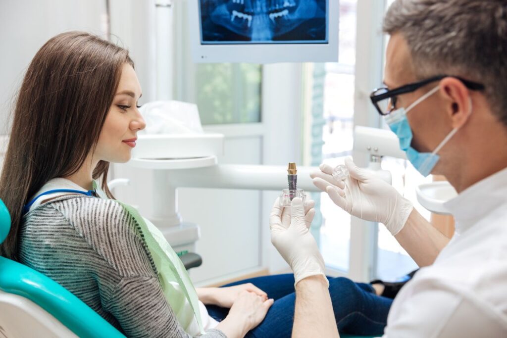 A dentist showing a woman a dental implant model